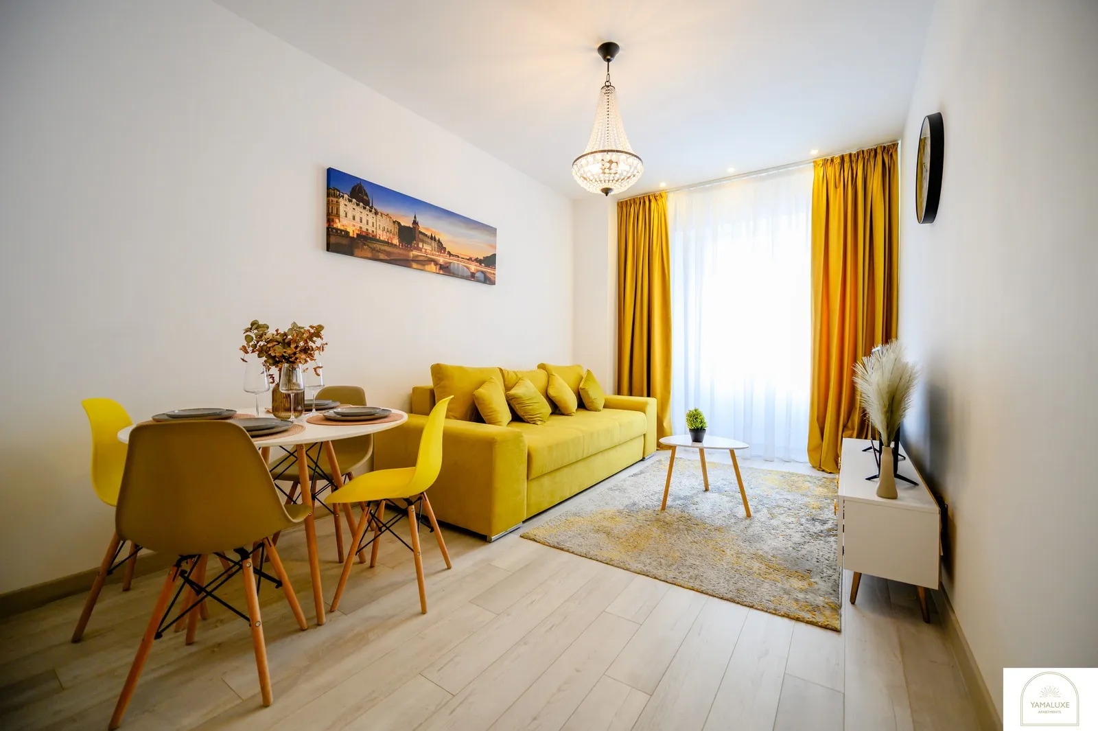 Living cu canapea galbenă, masă rotundă cu scaune galbene, candelabru de cristal și draperii muștar